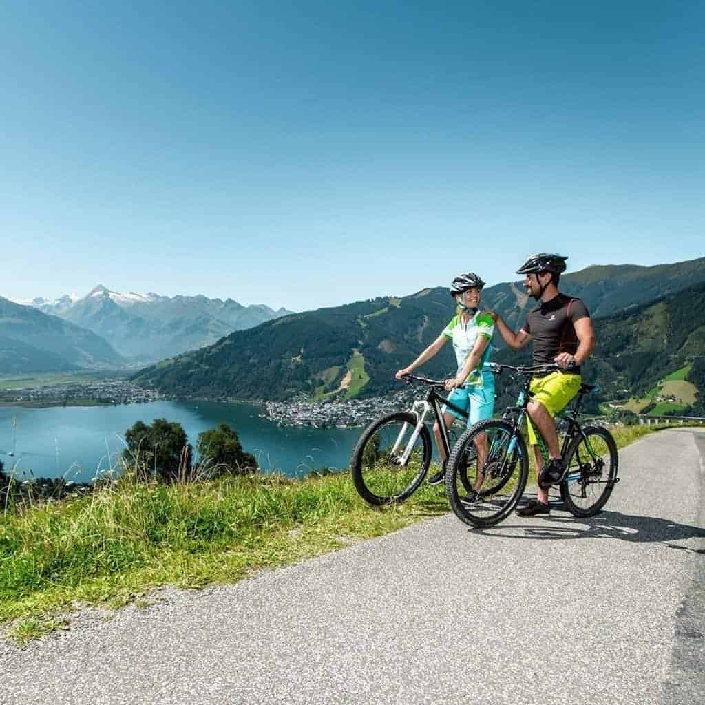 Radfahrer genießen den Ausblick auf Zell am See und die umliegenden Berge. Aktivurlaub im Erlhof.